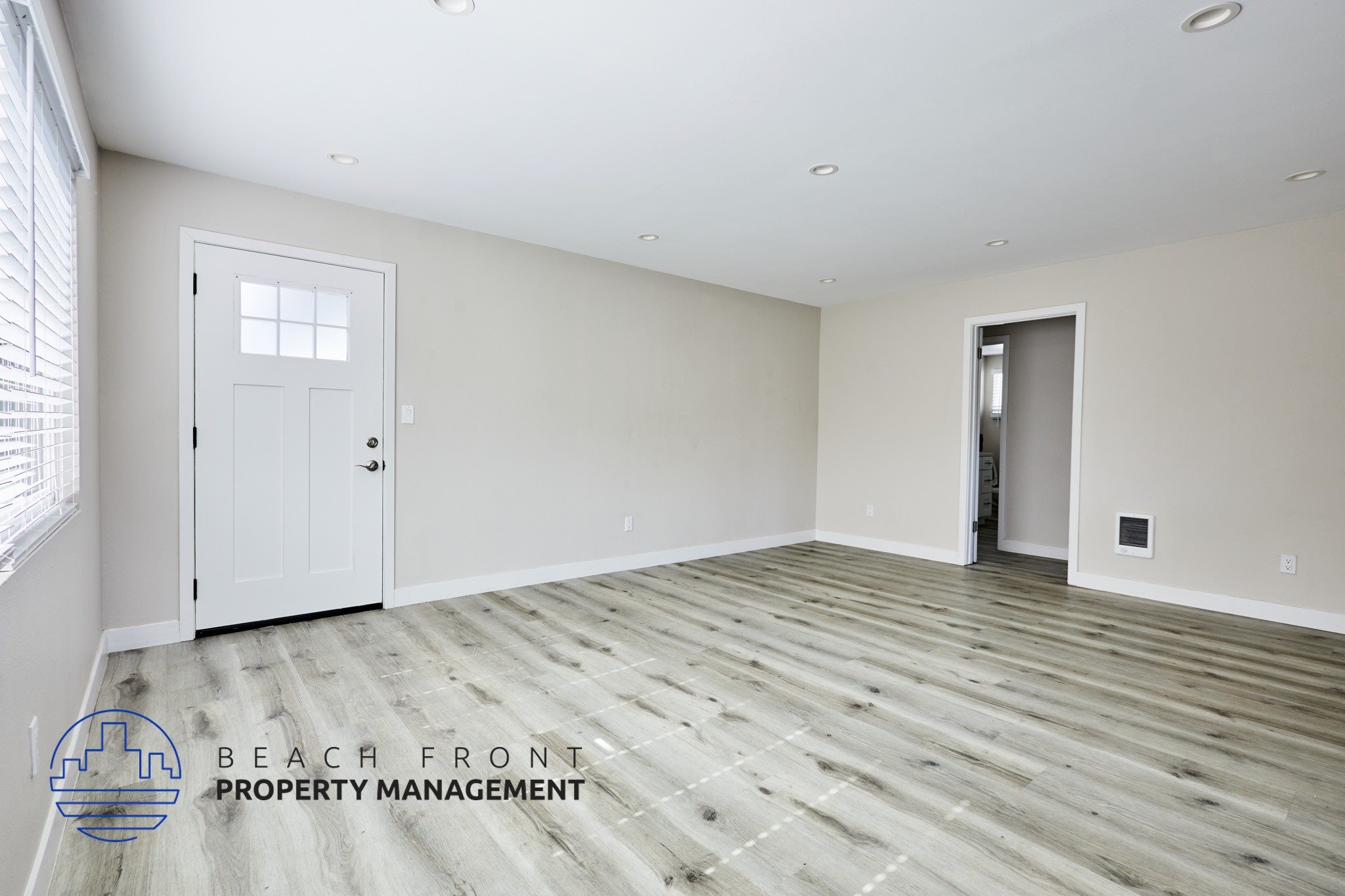 A spacious room with wooden flooring and two doors, one of which is open.